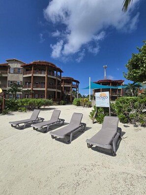 Hotel sul lungomare con numerosi balconi, una targa informativa e lettini sulla spiaggia.