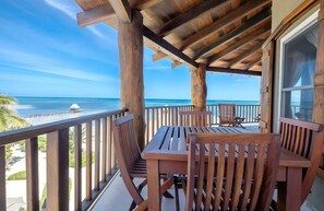 A wooden deck with a table and chairs, overlooking a beach and ocean. - Beach front, reef view, sleeps 6 (San Pedro - North)
