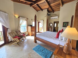 A bedroom with a wooden bed, a desk, a chair, a blue rug, and a ceiling fan. - Beach front, reef view, sleeps 6 (San Pedro - North)