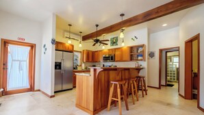 Eine Küche mit Holzausstattung, einer zentralen Kochinsel mit Barhocker, einem Deckenventilator und einem Fluchtwegzeichen.