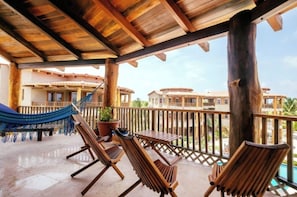 A wooden deck with lounge chairs and a hammock, overlooking a pool and buildings. - Colorful design and plenty of amenities, 3 bedrooms 3 baths (San Pedro - North)