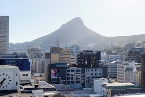 A cityscape with a prominent mountain in the background, modern buildings, and a clock tower. - Central Cape Town Apt With Views (Cape Town)