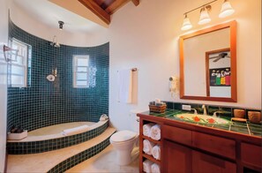 Un bagno con una vasca dal design curvo, uno specchio grande e un mobile contenitore in legno con asciugamani.