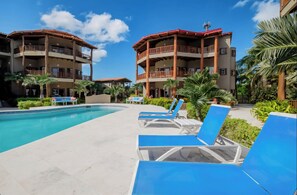 Ein Resort mit Schwimmbad, Liegestühlen und mehrstöckigen Gebäuden mit Balkonen.