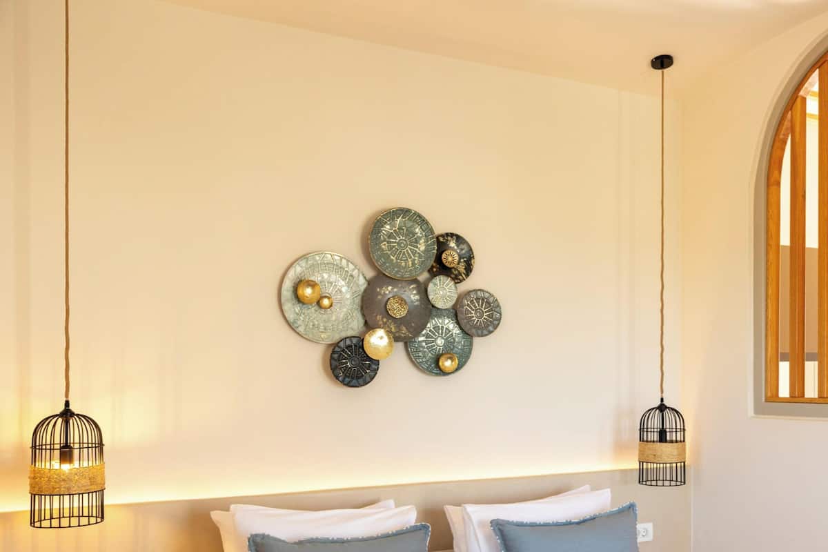 A room with a wall-mounted decorative plate arrangement, a wooden-framed window, and two hanging light fixtures.