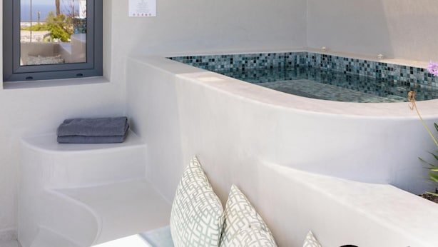 Un baño moderno con un jacuzzi integrado, una ventana con vistas a palmeras y un perchero.