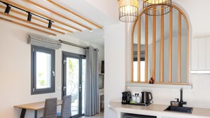 Una cocina moderna con lavavajillas, cafetera y fregadero. Hay una zona de comedor con mesa y sillas.