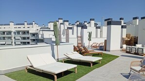 A rooftop terrace with lounge chairs, a small table, and a green artificial lawn. - Live Like a Local- Cozy 3BR in Suite Mijas (Las Lagunas de Mijas)