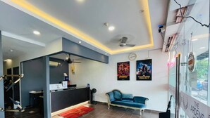 A hotel lobby with a reception desk, a blue sofa, a red rug, and two movie posters on the wall. - The Ardens Hotel - Pandan Johor Bahru (Johor Bahru)
