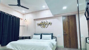 Une chambre à coucher avec un lit, un ventilateur de plafond, un luminaire fixé au mur et une porte en bois.