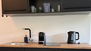 Una cocina con un lavamanos, una cafetera y un hervidor sobre la encimera.