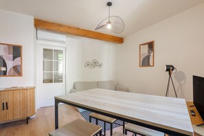 A modern room with a wooden dining table, a sofa, a wooden cabinet, and a ceiling fan.