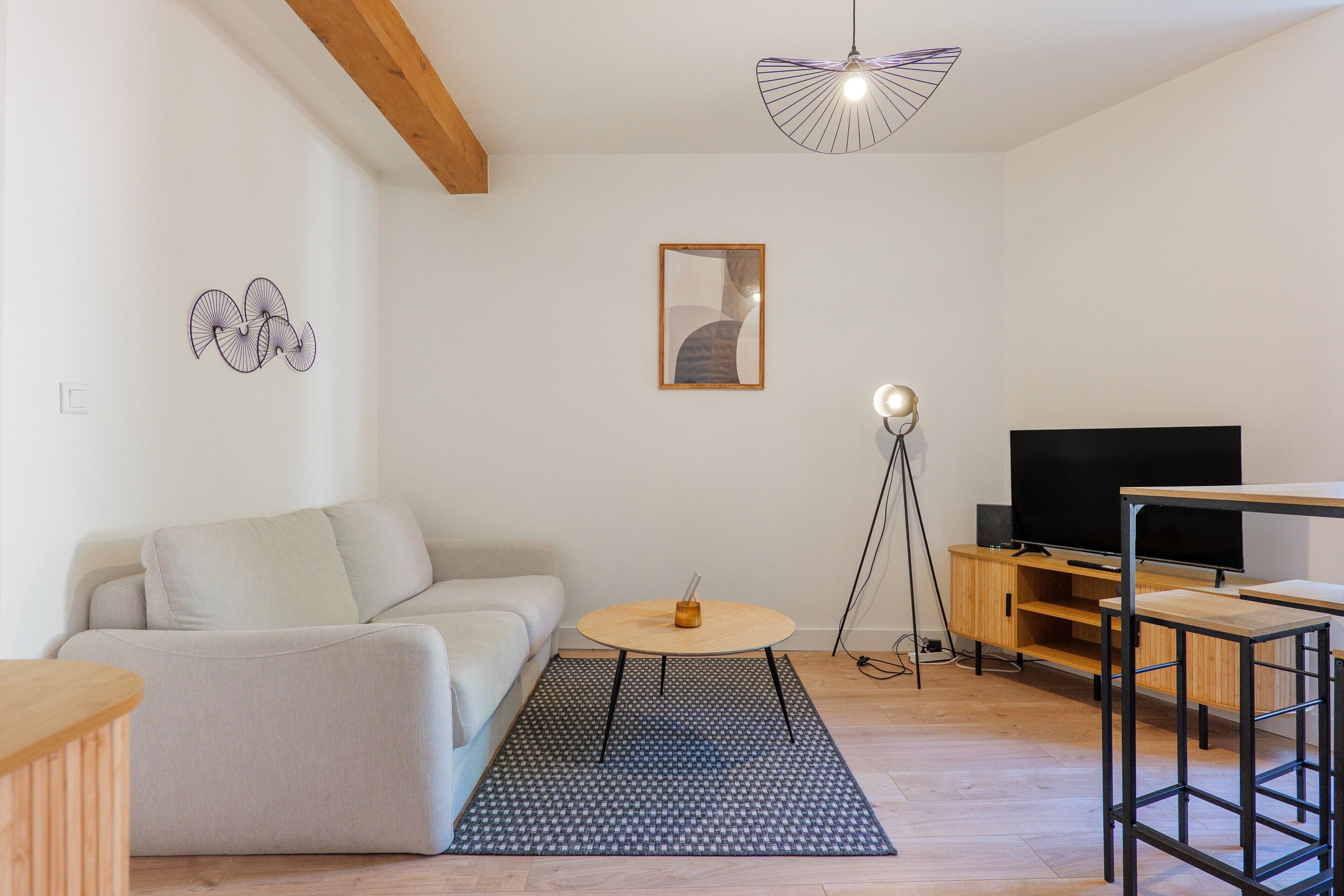Un salon moderne avec un canapé, une table basse ronde, un téléviseur et un meuble TV en bois.
