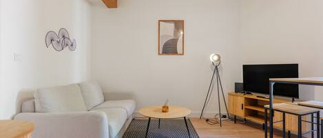 Un salon moderne avec un canapé, une table basse ronde, un téléviseur et un meuble TV en bois.