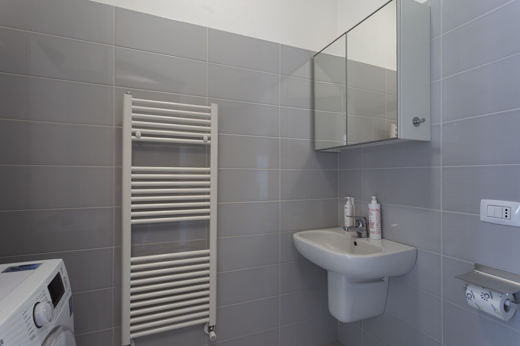 A bathroom with a white towel rack, a sink, and a mirror.
