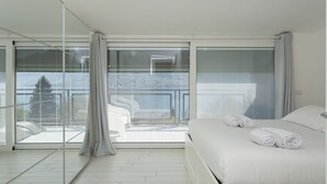 Ein modernes Hotelzimmer mit einem großen Bett, einer Glasabtrennung und Blick auf die Stadt.