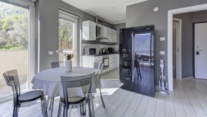 Eine moderne Küche mit weißen Schränken, einem Samsung-Kühlschrank und einem Essbereich mit rundem Tisch und Stühlen.