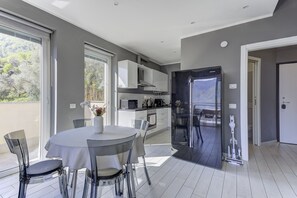 A modern kitchen with white cabinets, a Samsung refrigerator, and a dining area with a round table and chairs. - Open View Apartment by Wonderful Italy (Oliveto Lario)