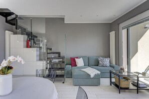 A modern living space with a sofa, a glass coffee table, and a staircase leading to an upper level. - Open View Apartment by Wonderful Italy (Oliveto Lario)