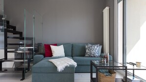 Ein modernes Wohnzimmer mit einem Ecksofa, einem Glastisch und einer eingebauten Bücherwand.