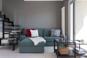 A modern living room with a sectional sofa, a glass coffee table, and a built-in bookshelf. - Open View Apartment by Wonderful Italy (Oliveto Lario)