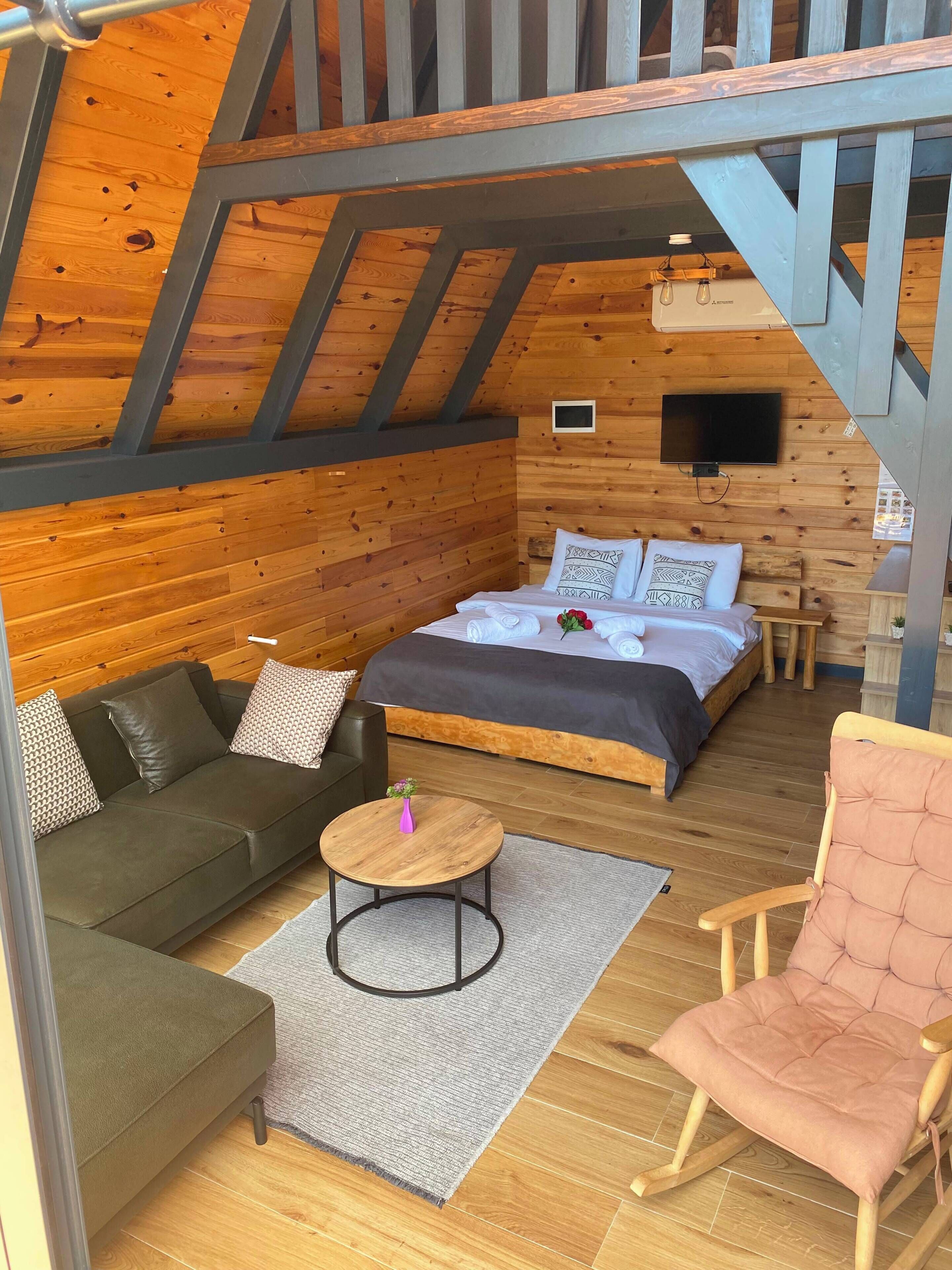 A cozy room with a bed, a sofa, a chair, a small table, and a television.