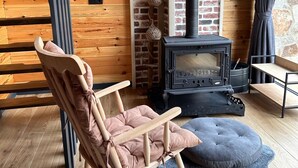 A cozy room with a wooden floor, a rocking chair, a fireplace, and a stone wall.