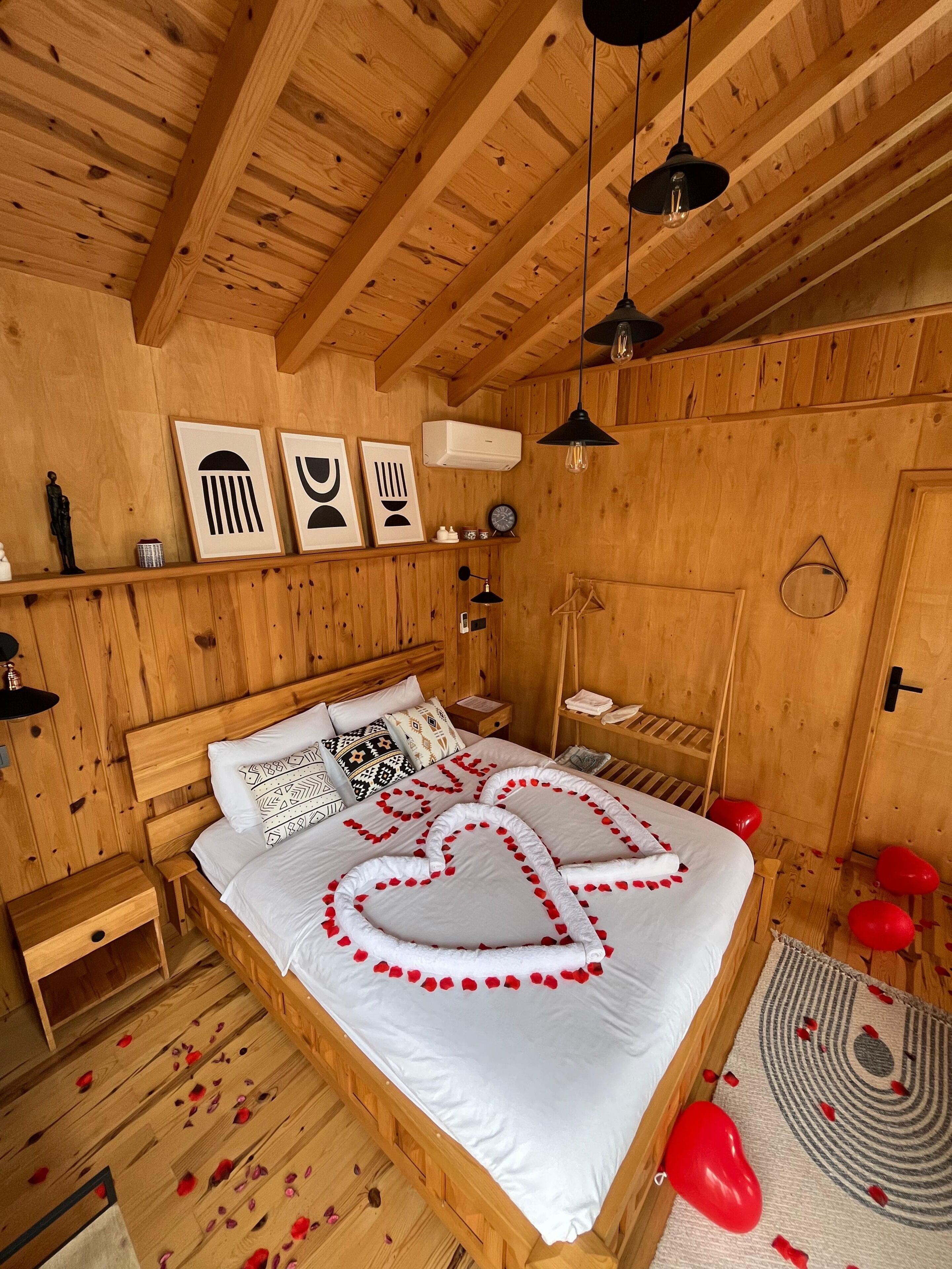 Une chambre à coucher aux murs lambrés, avec un lit, des tables de chevet, un luminaire suspendu et un climatiseur fixé au mur.