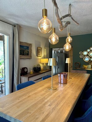 A wooden dining table with hanging light fixtures, a radio, and a lamp. - Villa les Lézards: Set on a private lot with a pool, not overlooked by neighbors (Bagard)