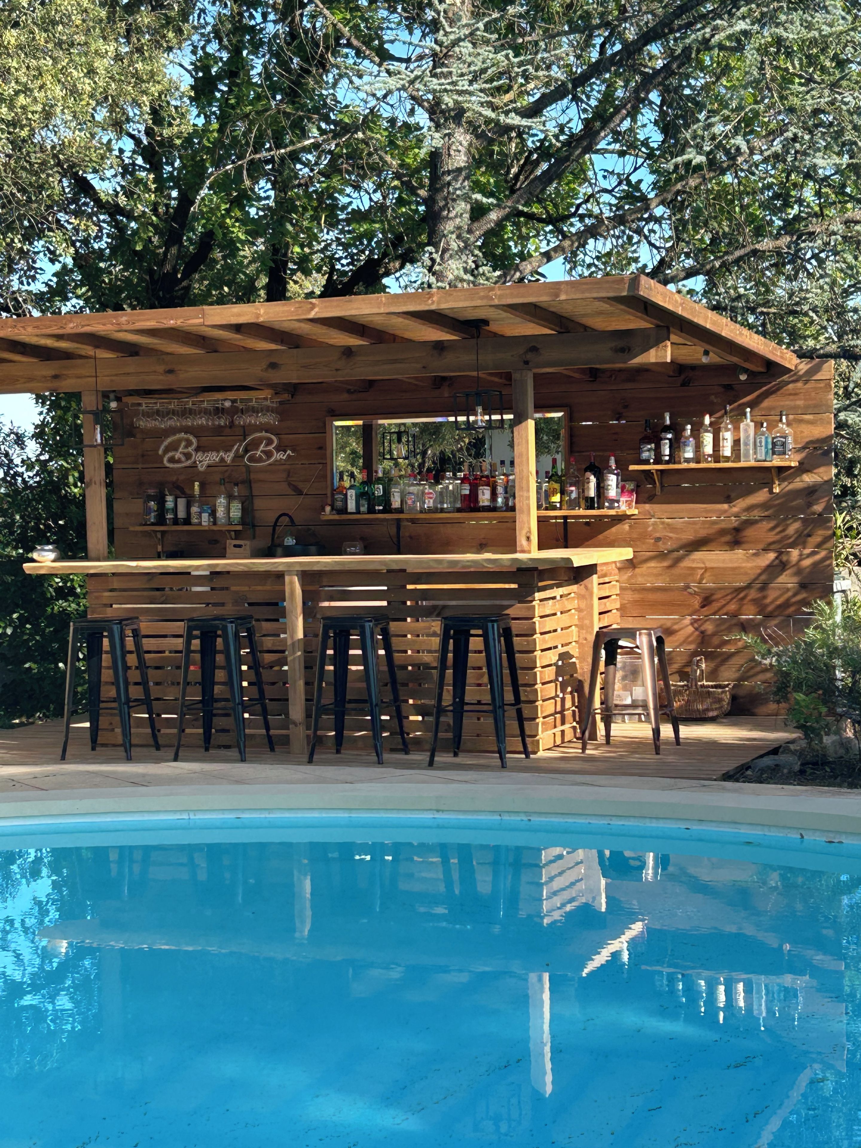 Una barra de madera con una piscina al frente.