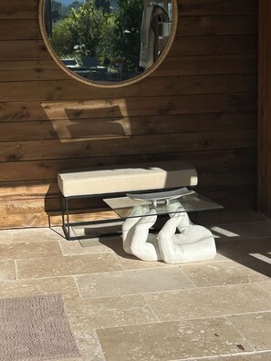 A bathroom with a wooden wall, a round mirror, a white sink, and a towel rack. - Villa les Lézards: Set on a private lot with a pool, not overlooked by neighbors (Bagard)