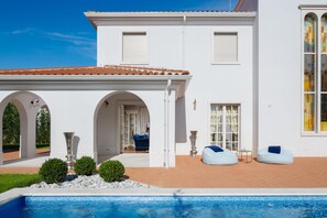 Ein weißes Gebäude mit Swimmingpool, Rundbogenöffnungen und einem Ziegeldach.