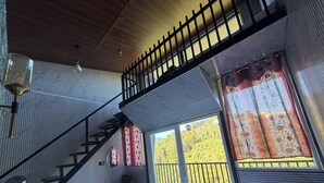 Una habitación con literas, una escalera, una ventana con cortinas y una lámpara colgante.