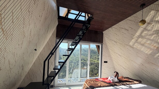 Una habitación con una cama, una escalera y un ventanal grande.