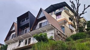 Un edificio residencial de varios pisos con balcones, techo plano y diseño inclinado.
