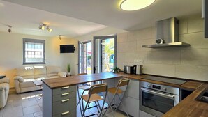 A modern kitchen with a central island, built-in oven, and a flat-screen TV. - Bungalow for 2 people with one bedroom, approx. 400 m to the beach (Graal-Müritz)
