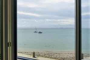 A view of a calm sea with two boats anchored, a sandy beach, and a cloudy sky. - Seaside Apartment - Les Viviers de la Houle (Cancale)