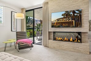 Ein modernes Wohnzimmer mit Kamin, einem Wand-Fernseher und Blick auf eine Berglandschaft.