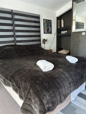 A modern hotel room with a large bed, a bedside table, a small plant, and a wall-mounted shelf. - Villa les Oliviers and its beautiful pool (Bagard)