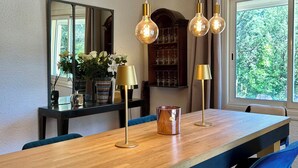 A dining area with a wooden table, blue chairs, hanging light fixtures, and a large mirror. - The Villa des OLiviers and its superb swimming pool (Bagard)