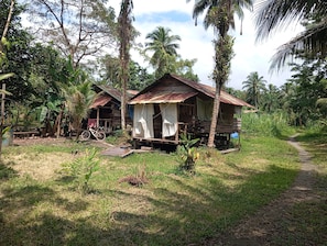 Two rustic wooden cabins surrounded by lush greenery and a clear sky. - Serene Oceanfront Cabin Retreat in Buenaventura (Buenaventura)