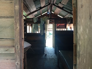 A wooden interior with a high ceiling, a bench, and hanging laundry. - Serene Oceanfront Cabin Retreat in Buenaventura (Buenaventura)
