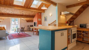Un'ampia cucina con soffitto in legno, un'isola centrale e un forno a microonde.
