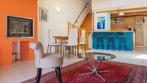Una cucina moderna con mobili in legno, un angolo bar e una zona pranzo con tavolo e sedie in vetro.