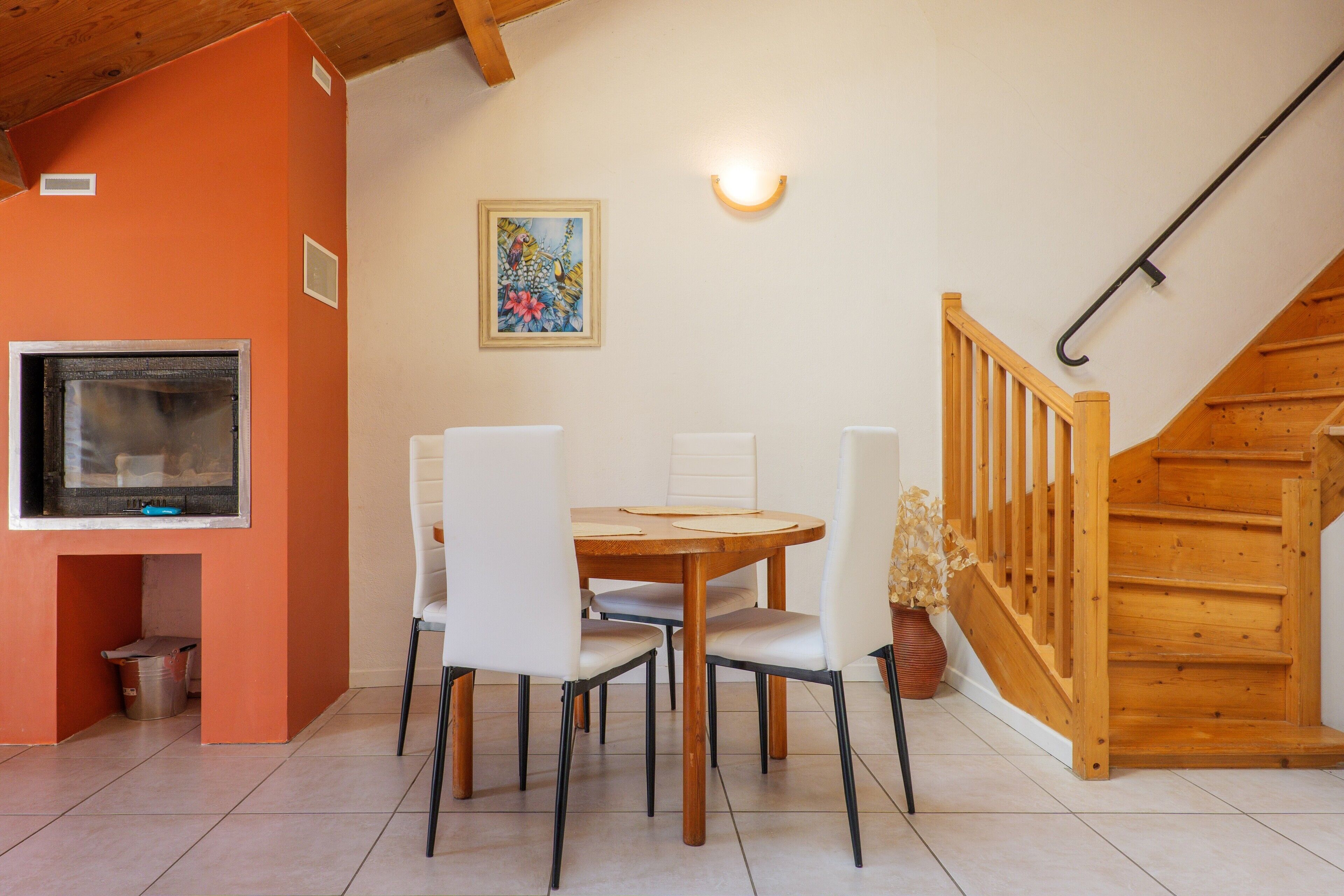 A dining area with a table and chairs, a television, and a staircase.