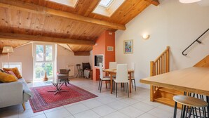 Un'ampia zona giorno con soffitto alto, lucernari, un tavolo da pranzo e una scala.