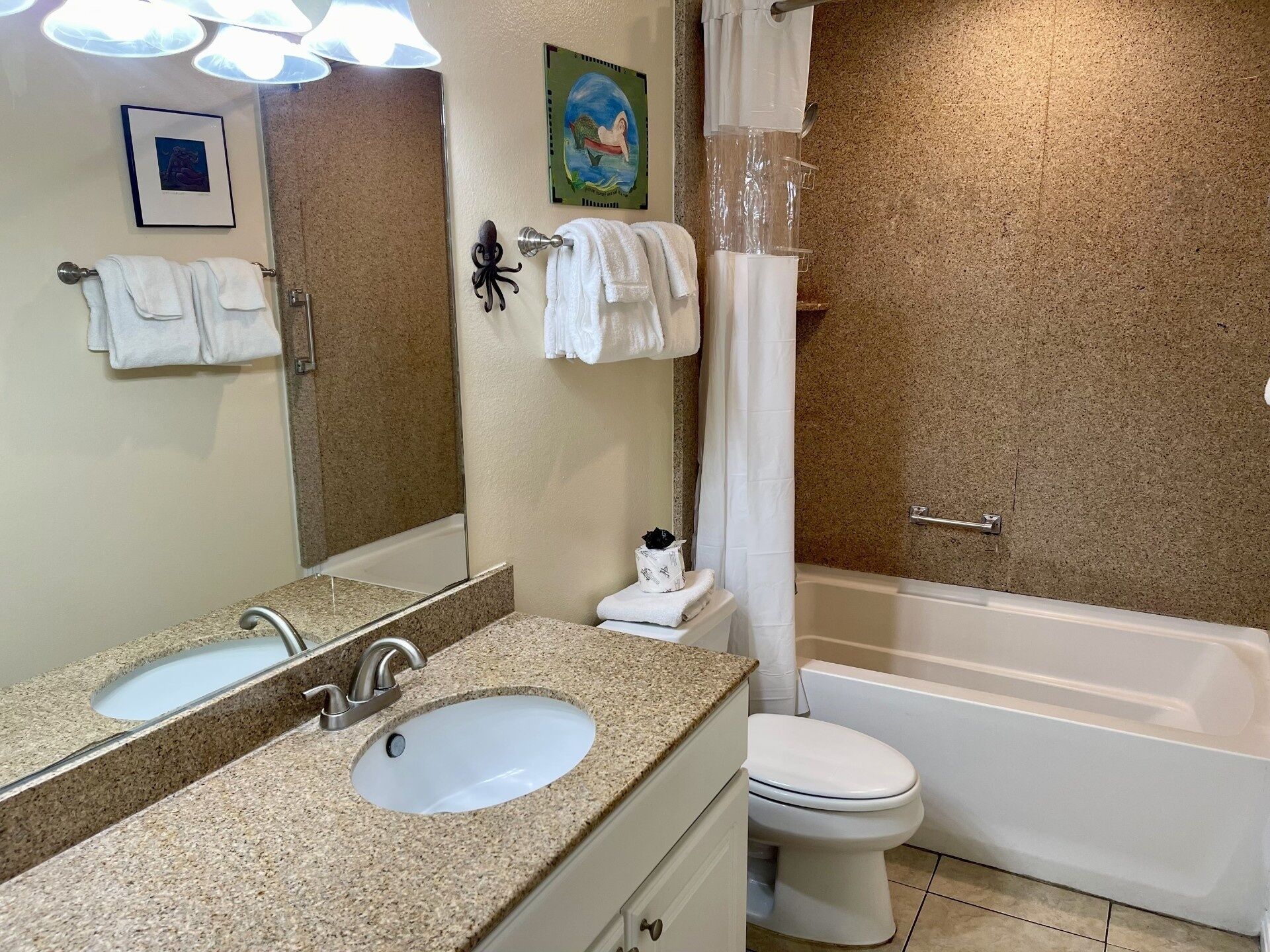 A bathroom with a double sink, a toilet, a bathtub, and a shower curtain.