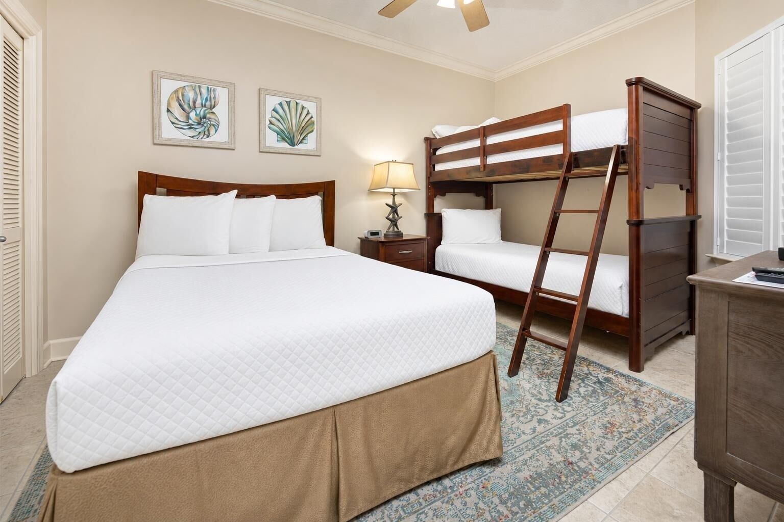 Une chambre d’hôtel avec un grand lit, un lit plus petit, une échelle, un bureau et une table de chevet.