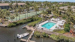 An aerial view of a resort with a swimming pool, tennis courts, and a dock area. - First-floor, snowbird-friendly townhouse w/ shared pool, WiFi, central AC, & W/D (Bokeelia)