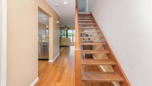 A wooden staircase leading to a second floor, a kitchen with stainless steel appliances, and a living area with a sofa and a ceiling fan. - First-floor, snowbird-friendly townhouse w/ shared pool, WiFi, central AC, & W/D (Bokeelia)